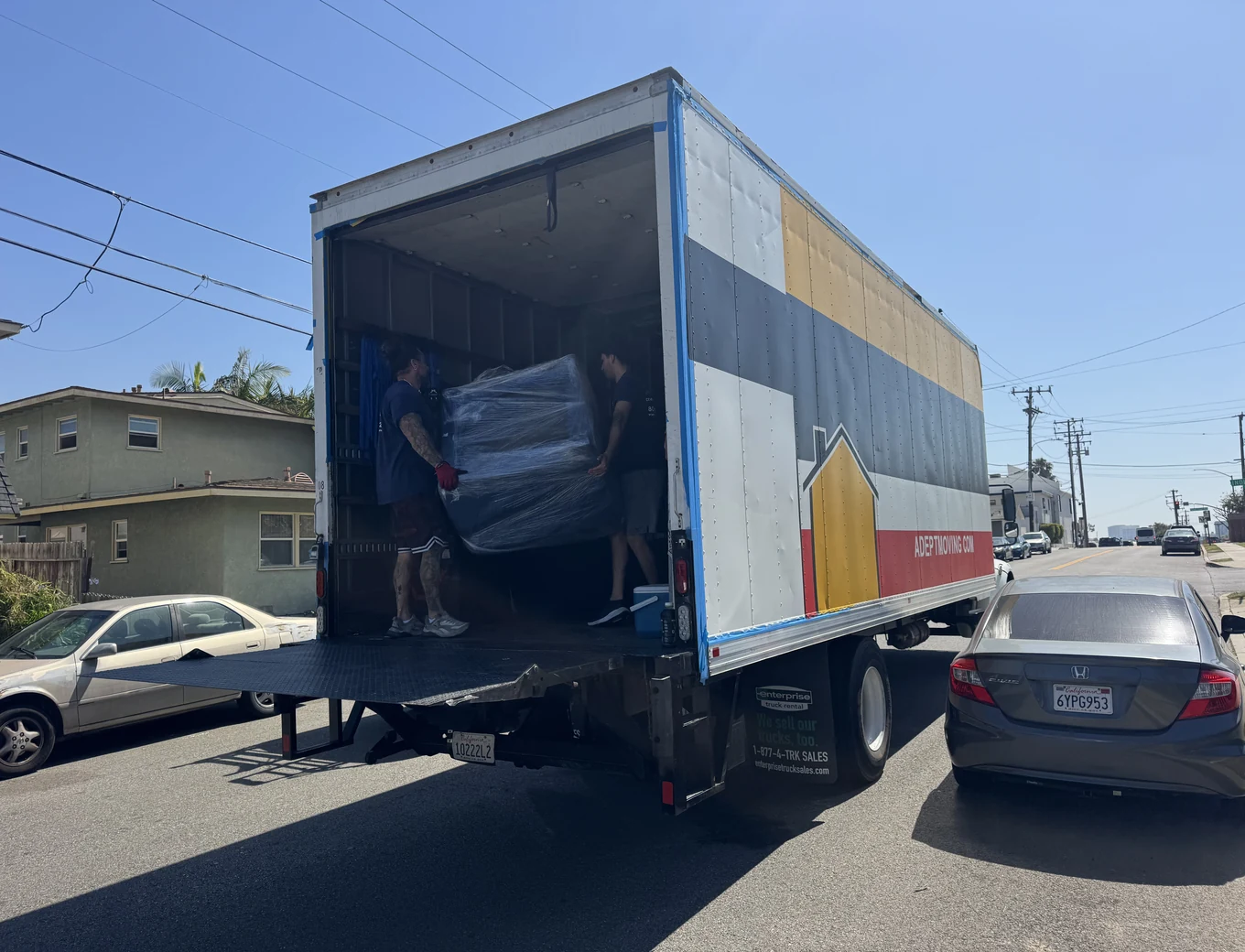 Adept Moving crew loading shrink-wrapped furniture onto the truck liftgate on East Maple Avenue in El Segundo, 90245