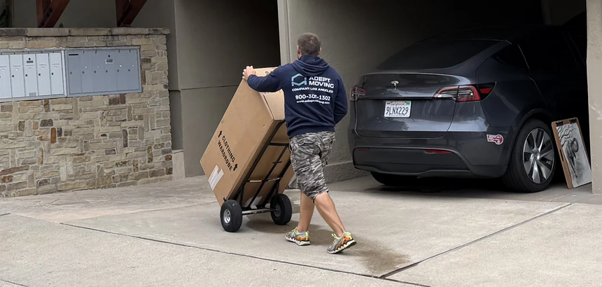 Adept mover moving a boxed item on a hand truck to a carport on Jasmine Street in Laguna Beach, 92651