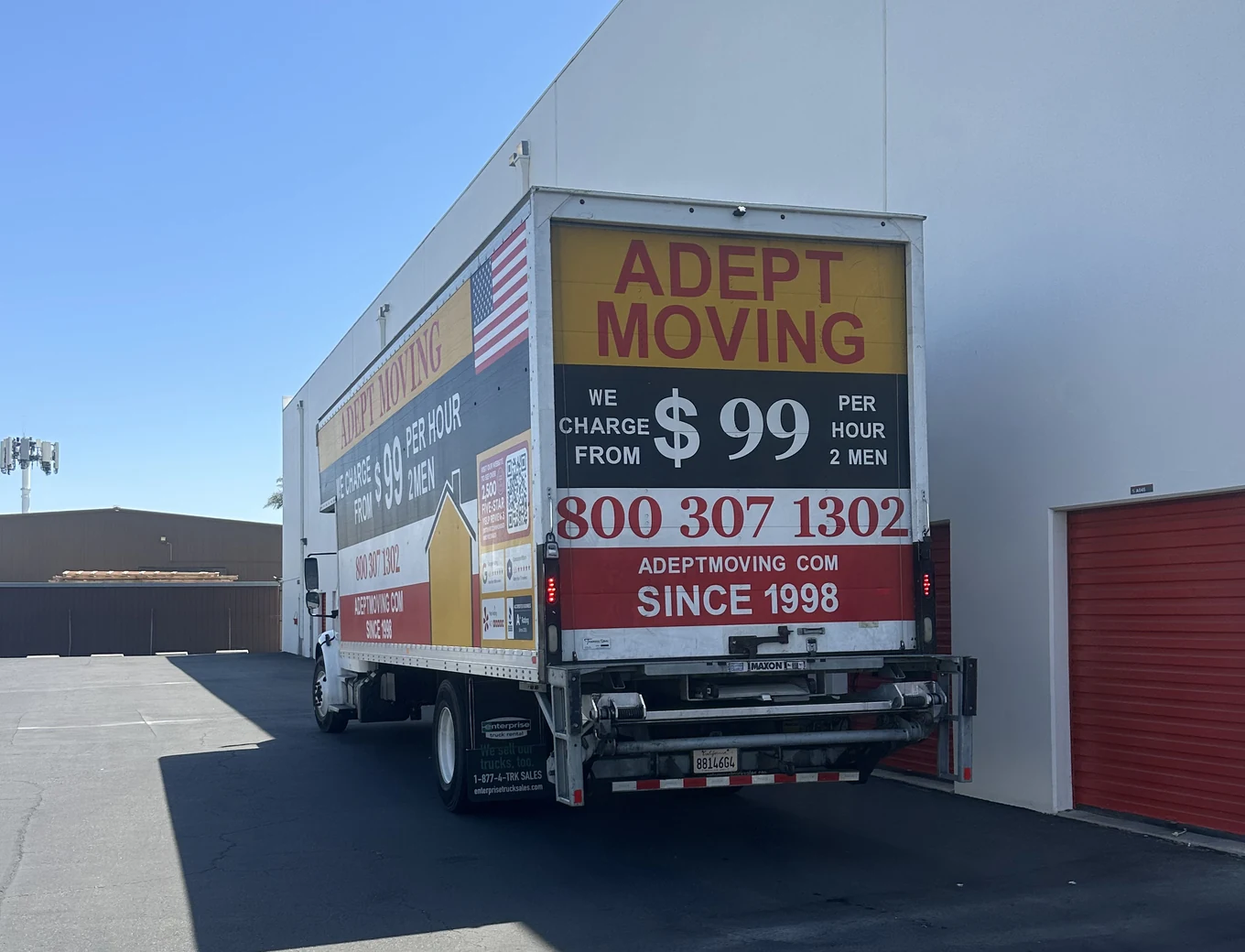 Adept Moving $99 branded box truck, rear three-quarter view, on Cerritos Avenue in Los Alamitos, 90720