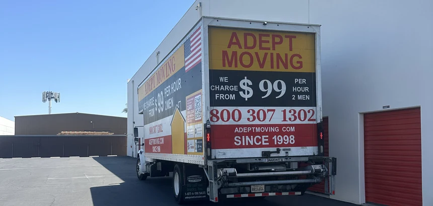 Adept Moving $99 branded box truck, rear three-quarter view, on Cerritos Avenue in Los Alamitos, 90720