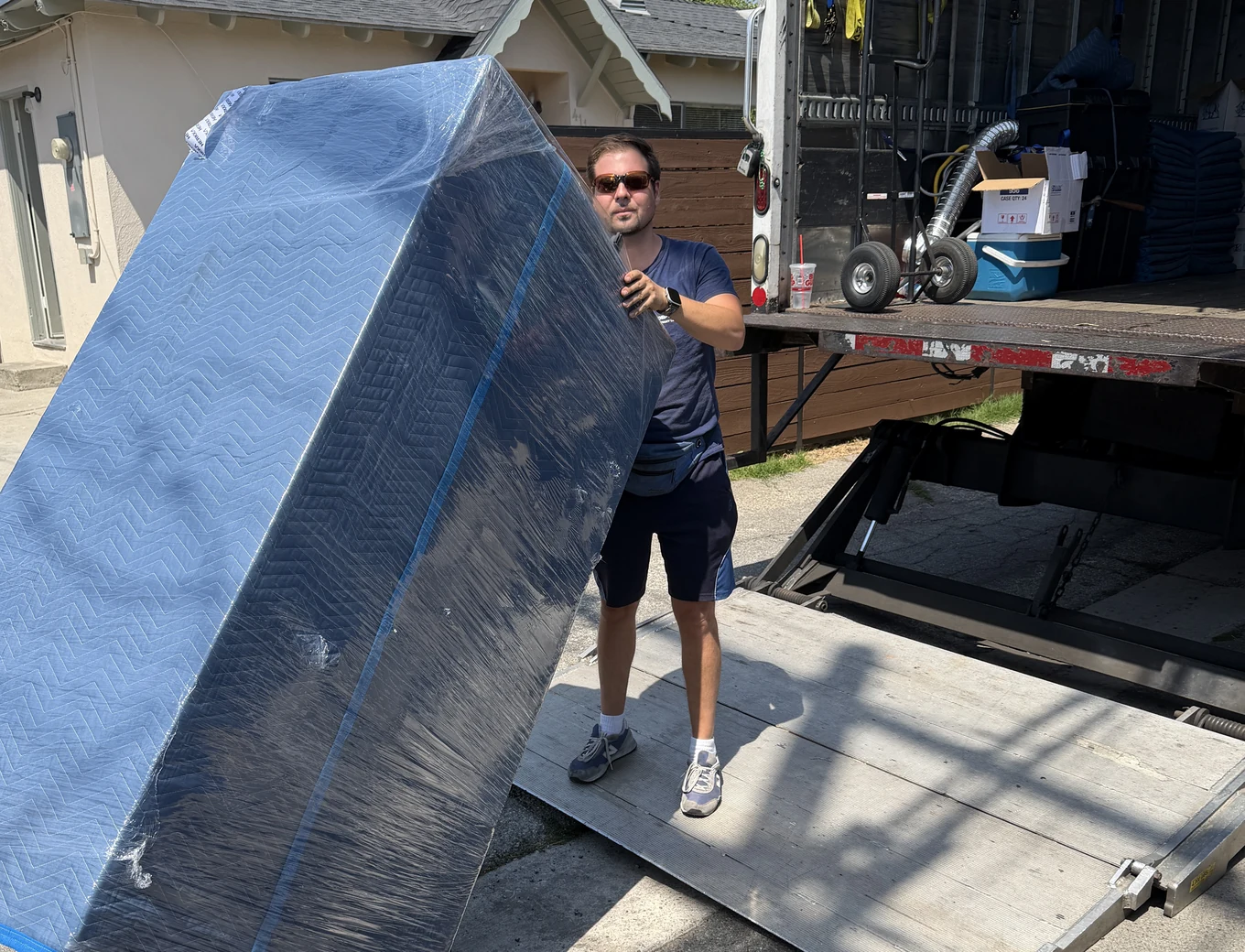 Adept mover with a blanket-wrapped mattress at the truck liftgate on South Alta Vista Avenue in Monrovia, 91016