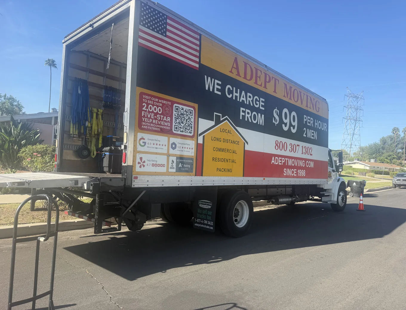 Adept Moving truck with the liftgate down on a street of single-story ranch homes in Reseda