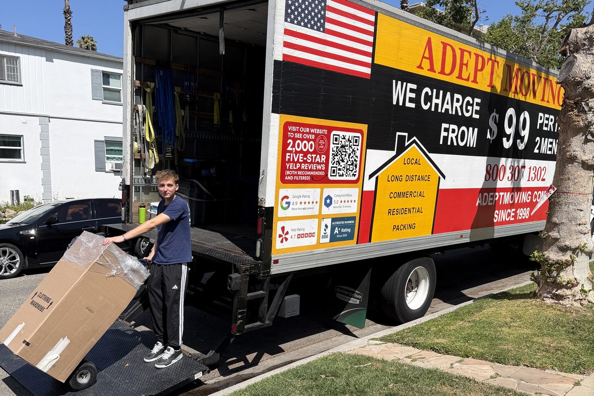 Adept Moving crew member wheeling a wardrobe box up the truck ramp on South Oakhurst Drive in Beverly Hills