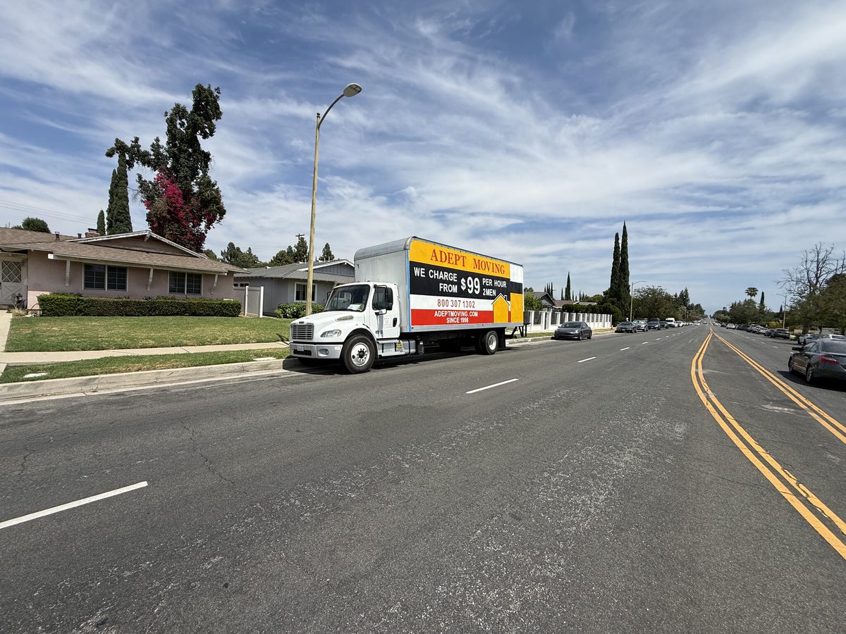 Adept Moving truck parked on a wide residential street with ranch homes