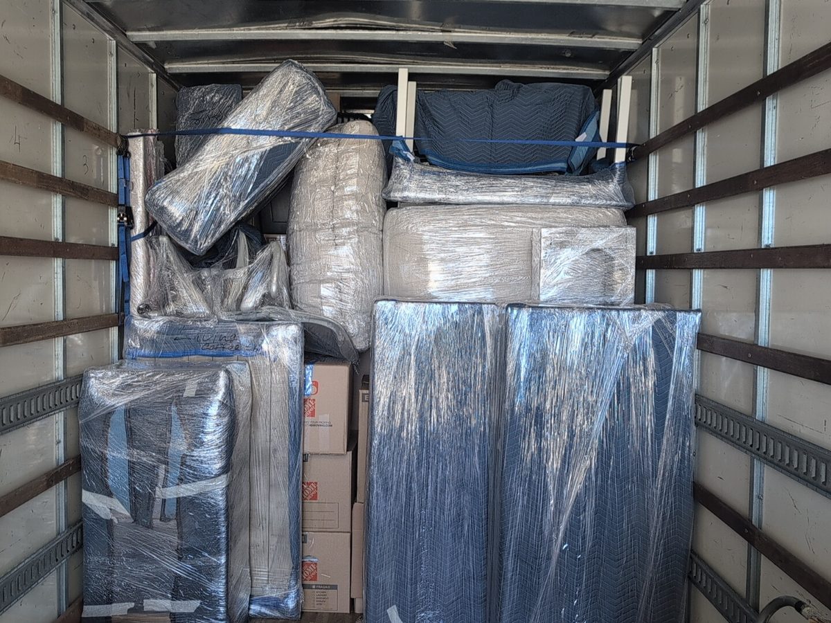 Blanket-wrapped and stretch-wrapped furniture loaded inside the Adept Moving truck