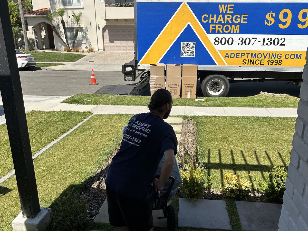 Adept Moving mover heading to the truck with boxes staged at the curb in Manhattan Beach