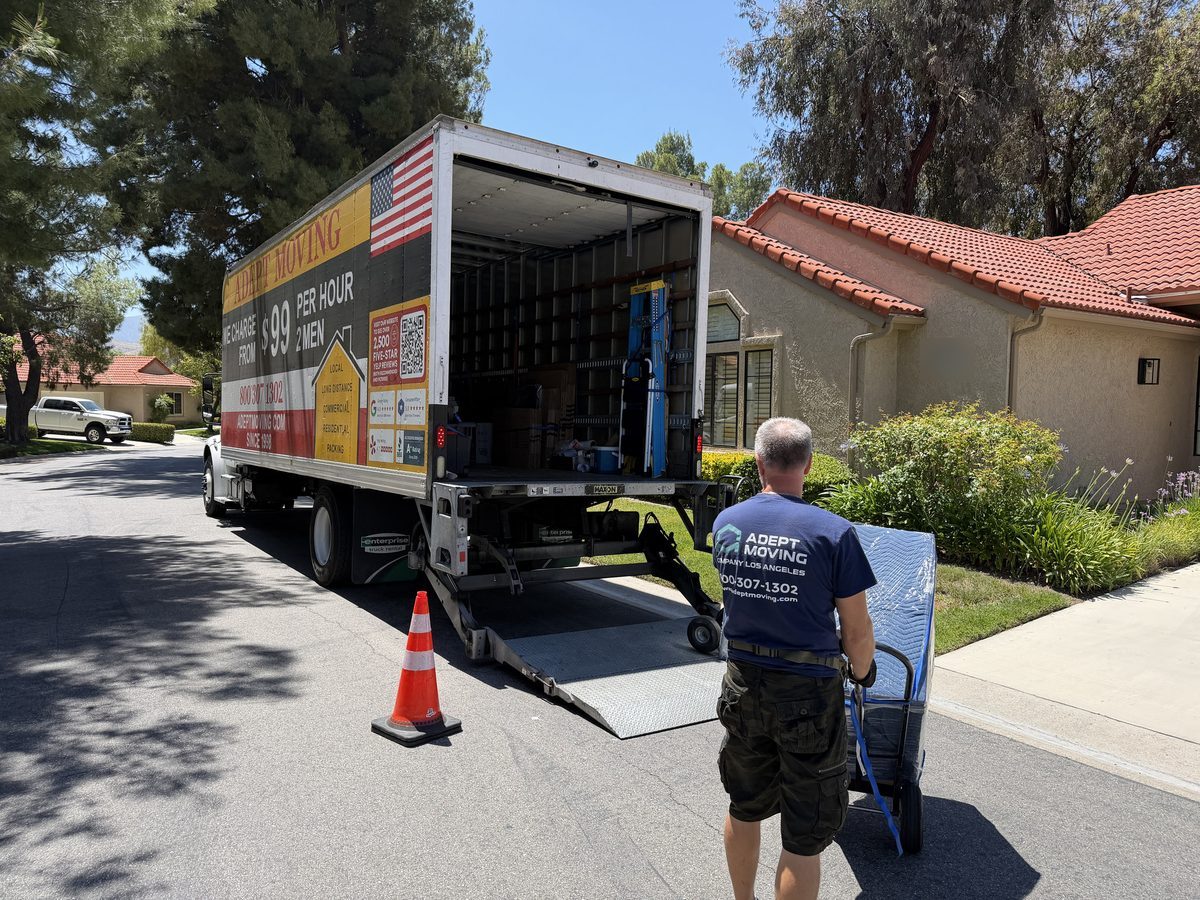 Adept Moving truck with the liftgate down and a cone out by the condominium units in Santa Clarita