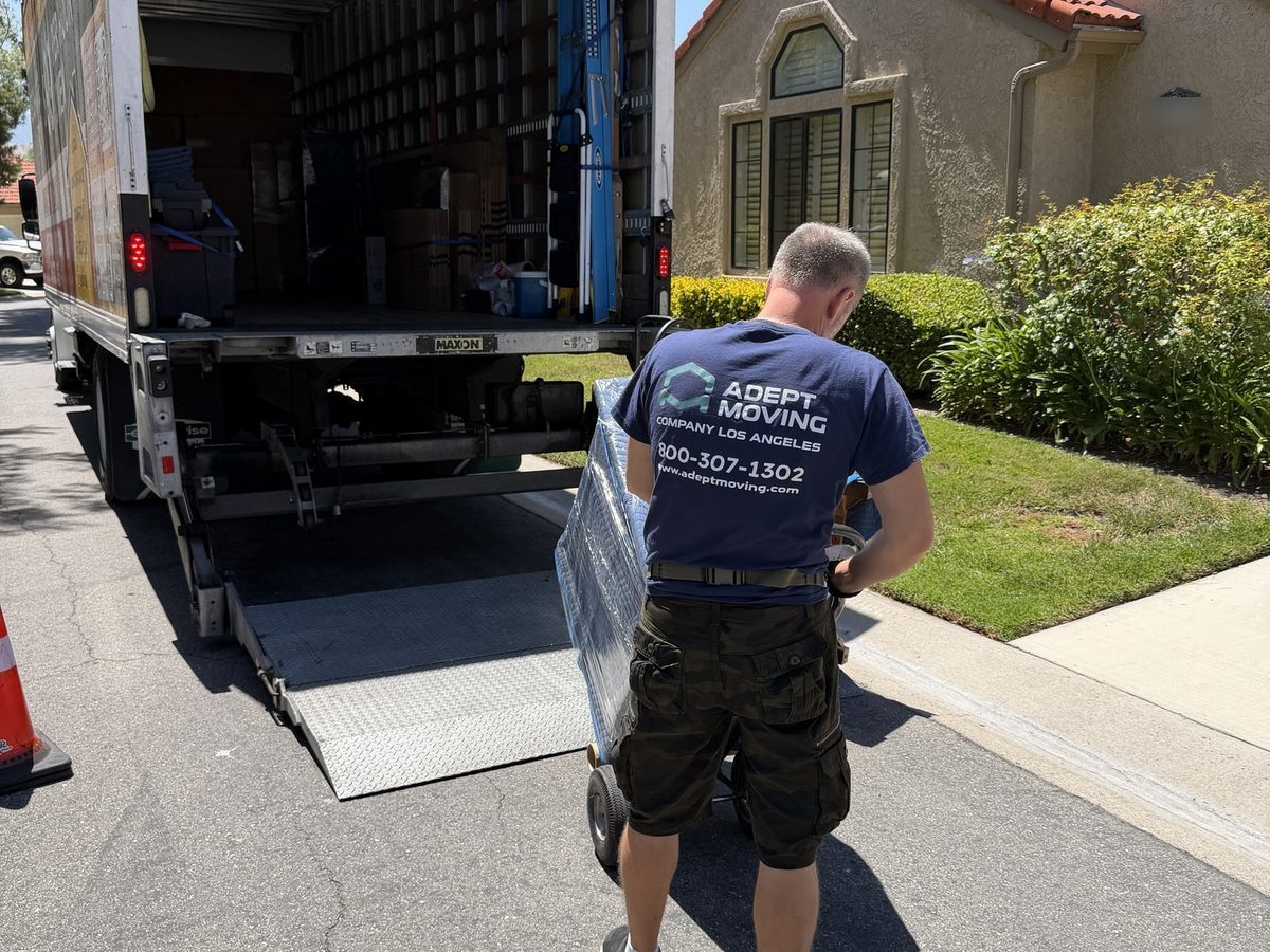 Adept Moving mover wheeling a wrapped piece on a dolly to the truck liftgate
