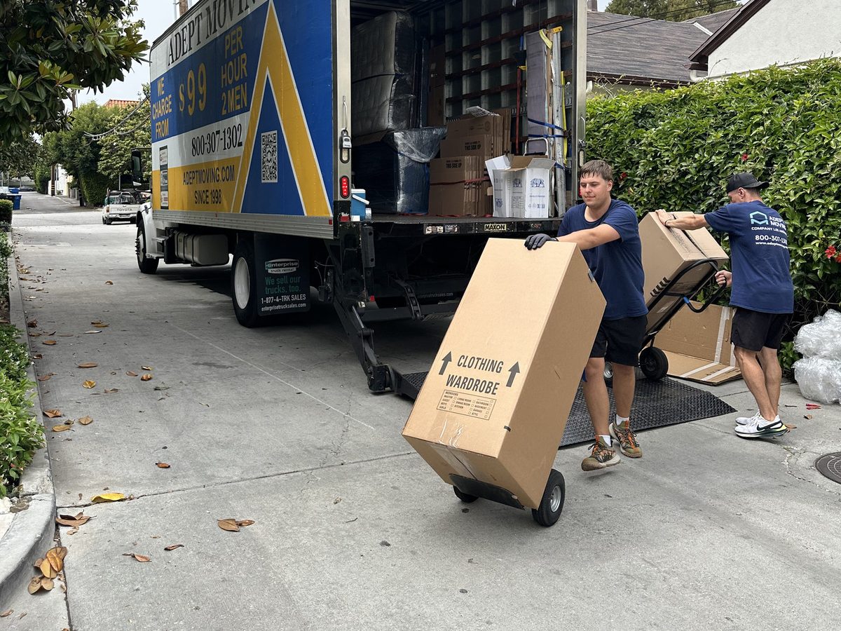 Adept Moving movers unloading wardrobe cartons from the truck liftgate on hand trucks