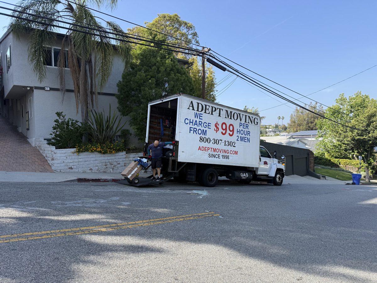 Adept Moving mover rolling boxes on a hand truck past a retaining wall to the truck
