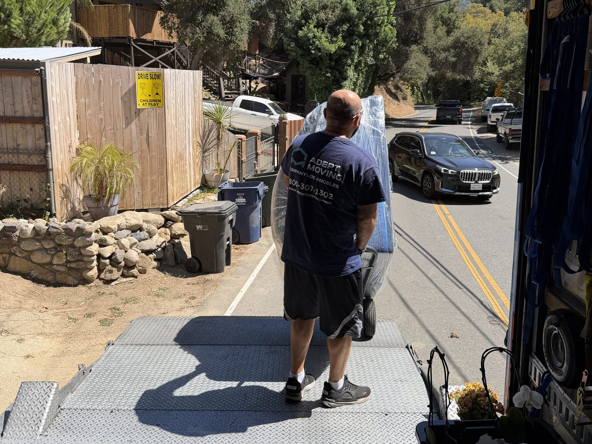 Adept Moving mover loading wrapped furniture by hand onto the truck in Topanga