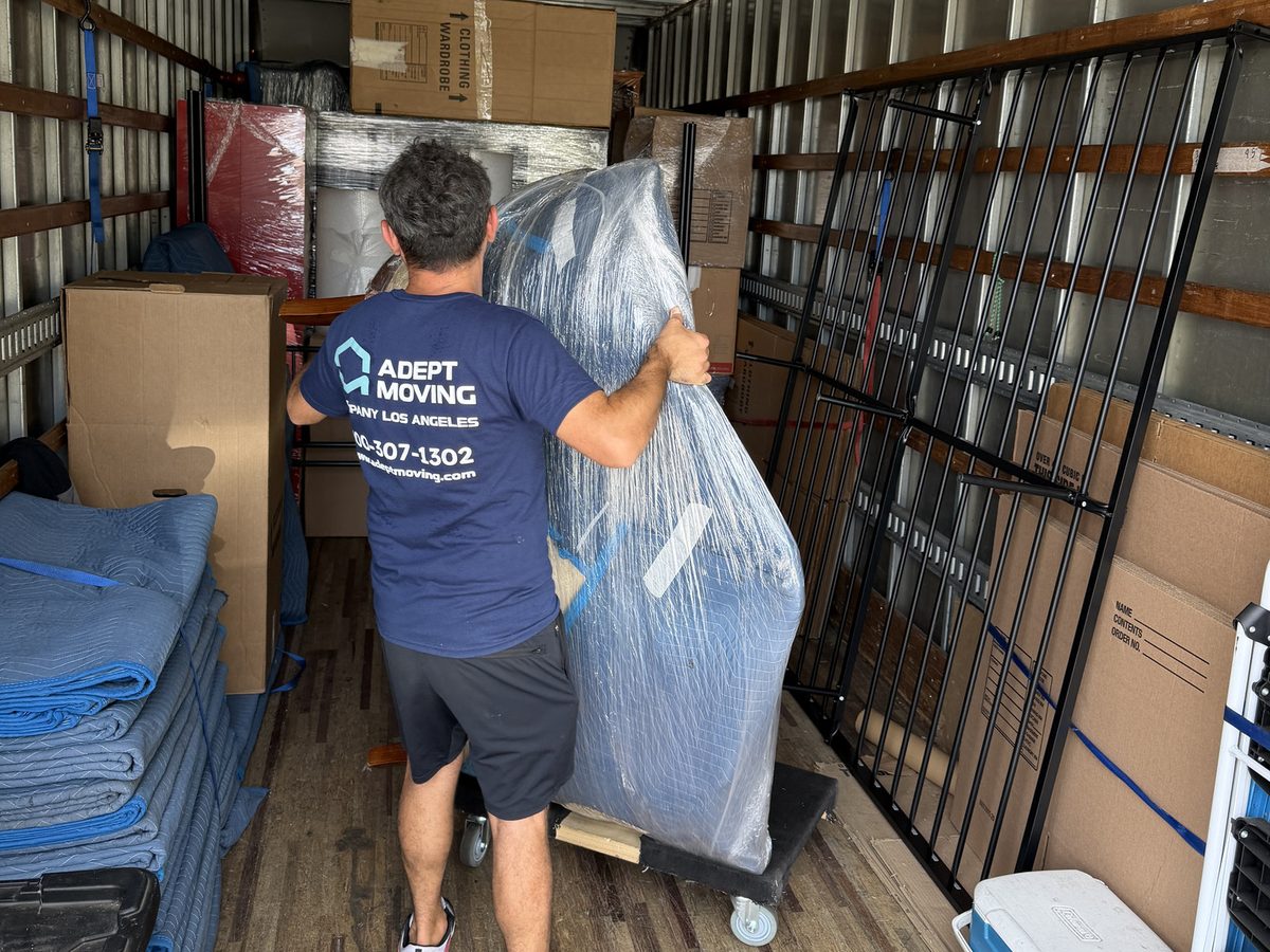 Adept Moving mover loading wrapped furniture inside the truck next to the bed frame rails