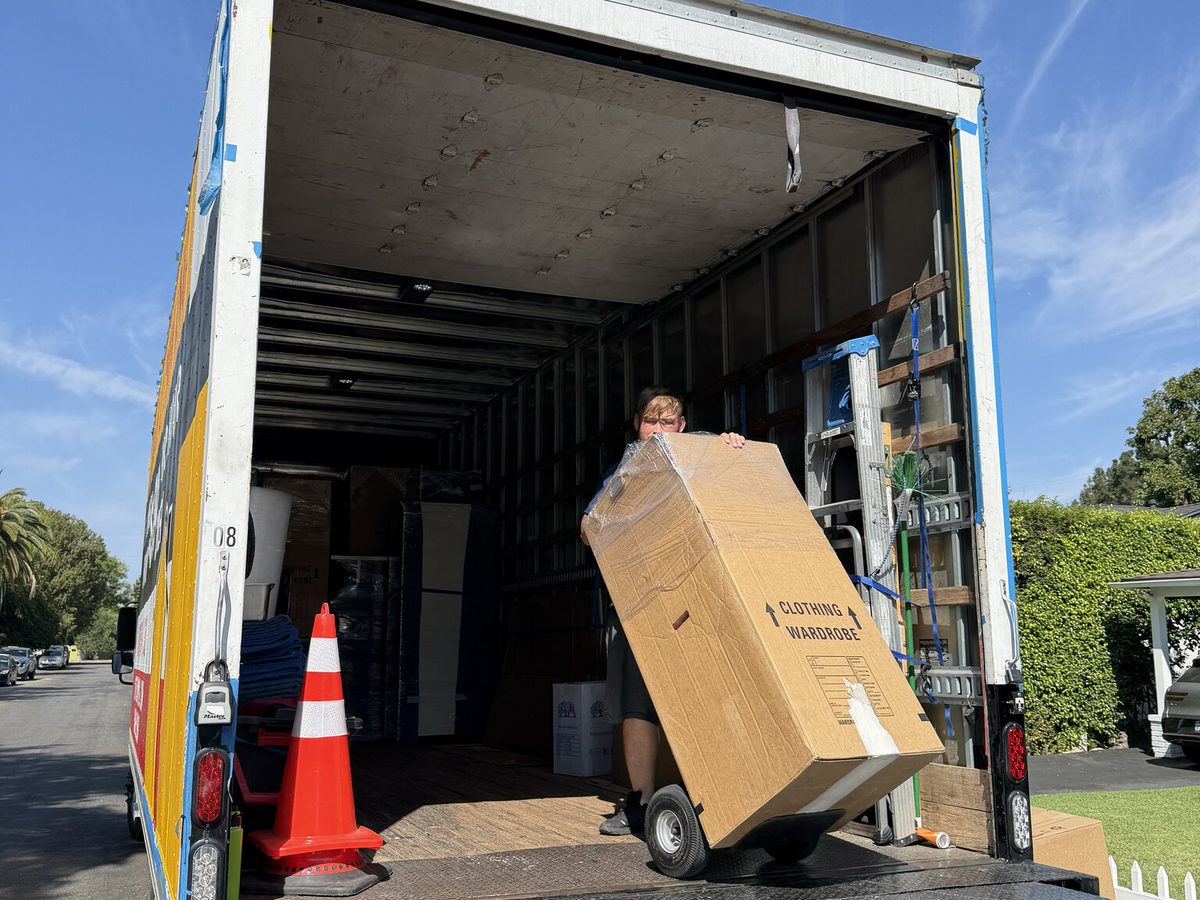 Adept Moving mover wheeling a wardrobe carton onto the truck on a hand truck