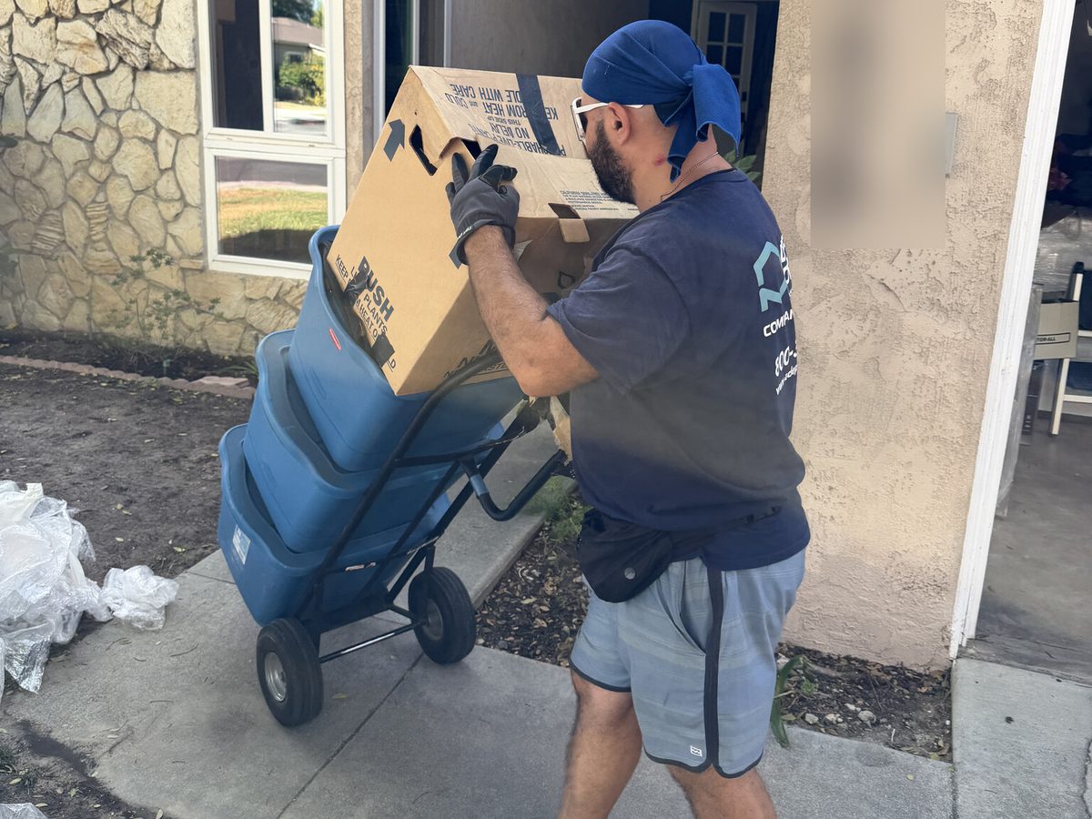 Adept Moving mover wheeling boxes out of the house on Rhodes Avenue on a hand truck