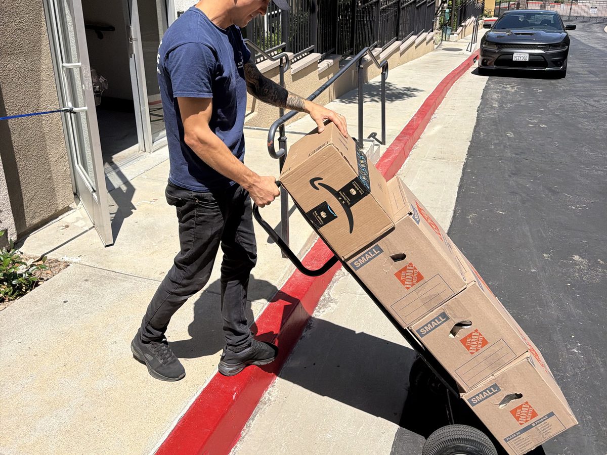 Adept Moving mover wheeling Home Depot moving boxes on a dolly to the truck