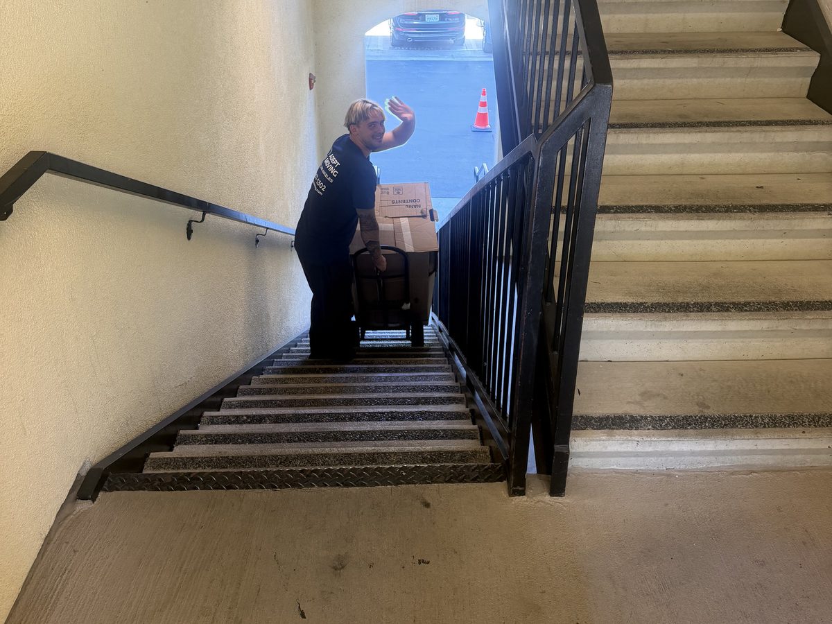 Adept Moving mover at the foot of the townhome stairs with a loaded dolly