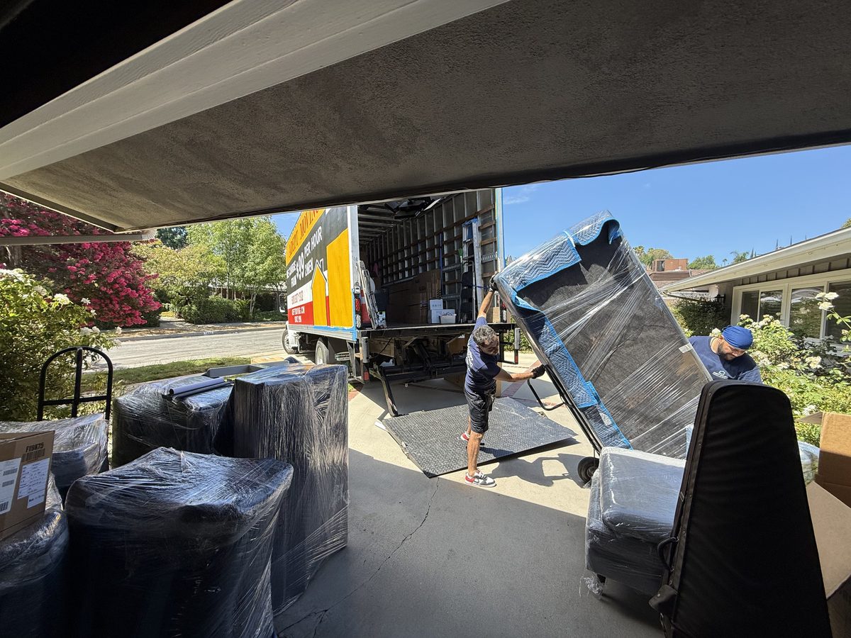 Adept Moving mover loading wrapped furniture from the garage onto the truck liftgate