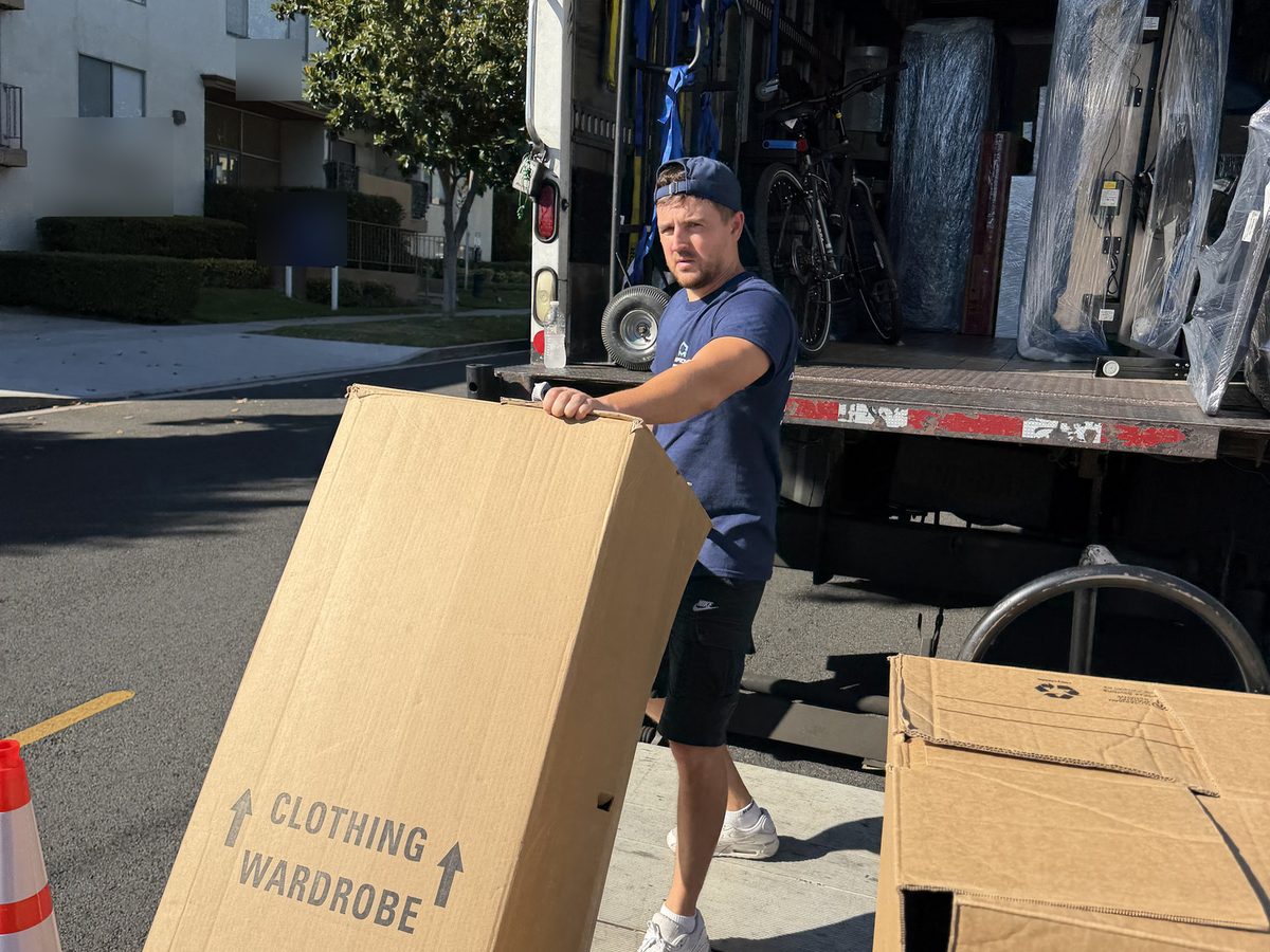 Adept Moving mover loading a wardrobe carton onto the truck liftgate on East Magnolia Boulevard