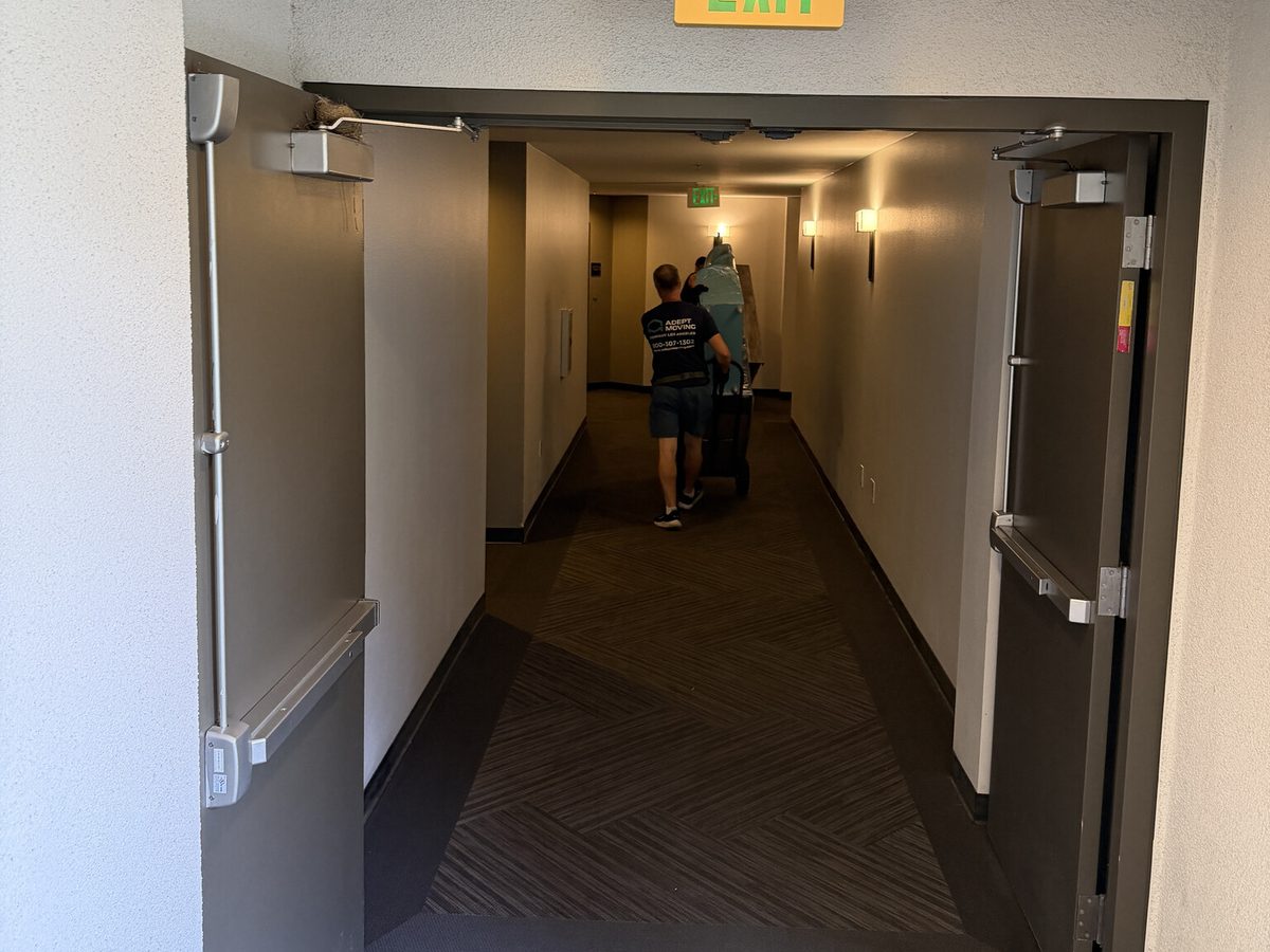 Adept Moving movers carrying furniture down the apartment corridor on North Buena Vista Street