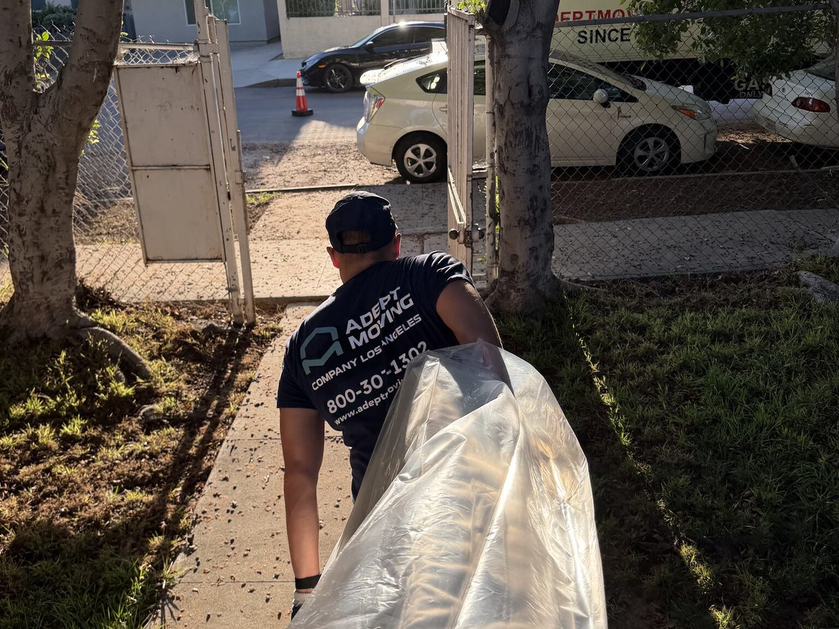 Adept Moving mover carrying a wrapped piece out to the truck on Willowcrest Avenue