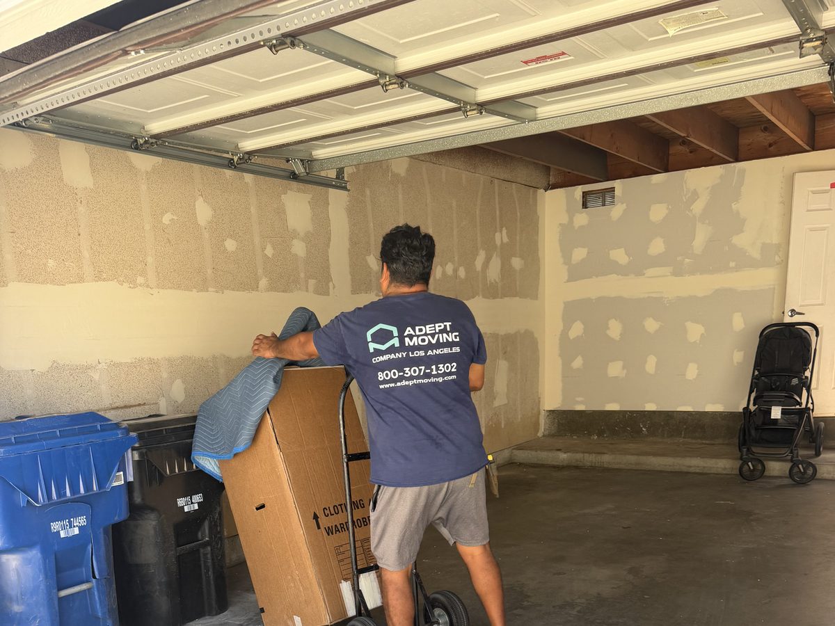 Adept Moving mover wheeling a wrapped piece on a hand truck out of the private garage