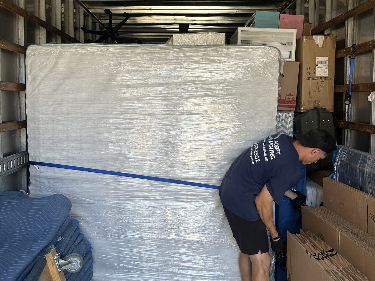 Adept Moving mover loading inside the truck next to the stretch-wrapped mattress