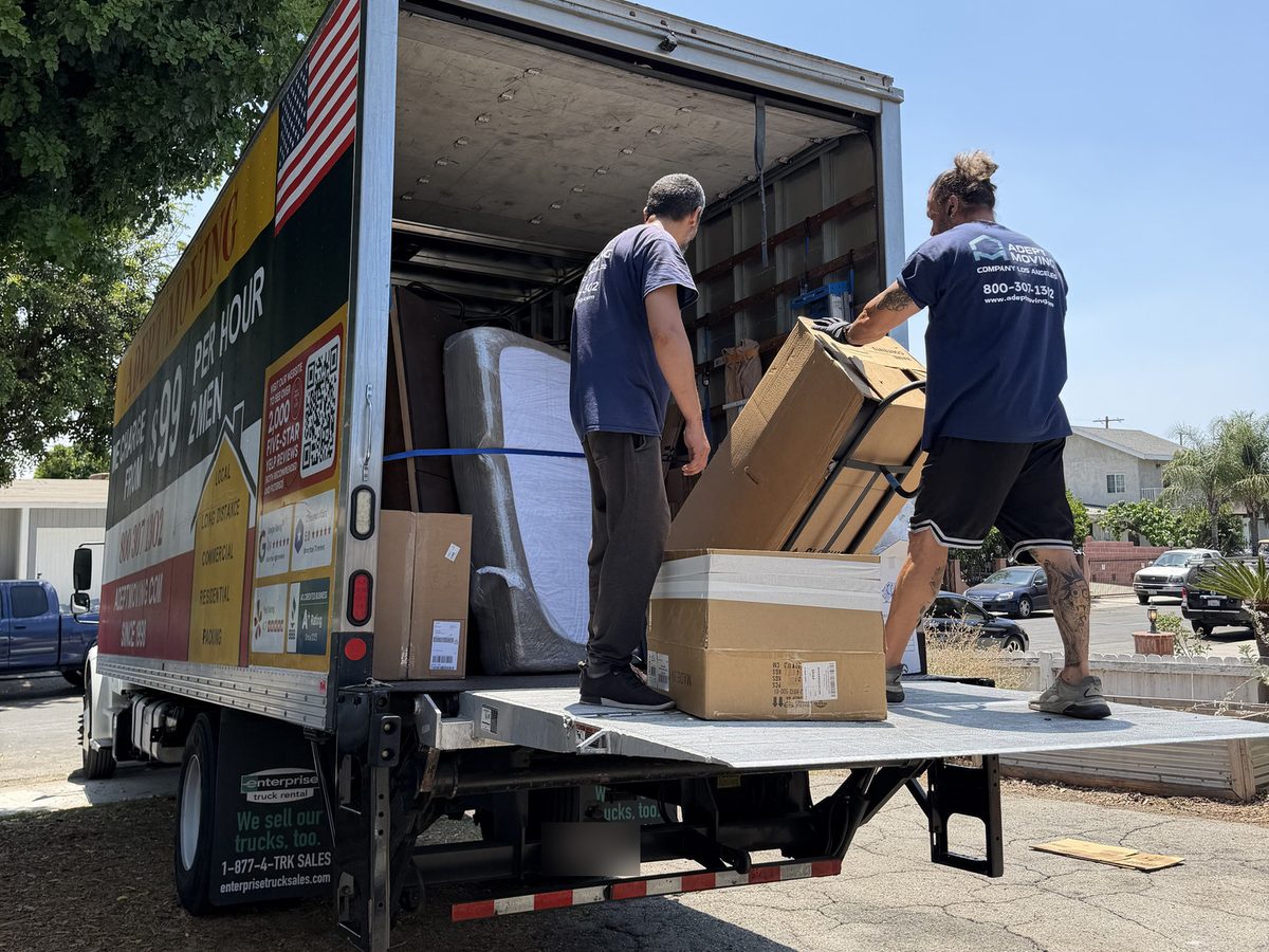 Adept Moving movers loading boxes on a hand truck from the liftgate into the truck