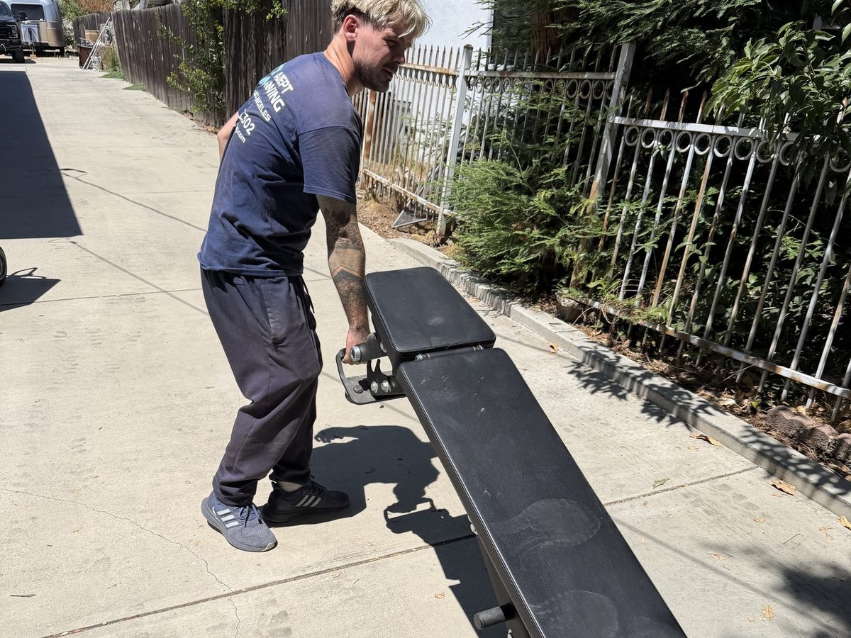 Adept Moving mover rolling the adjustable weight bench along the driveway in Pasadena