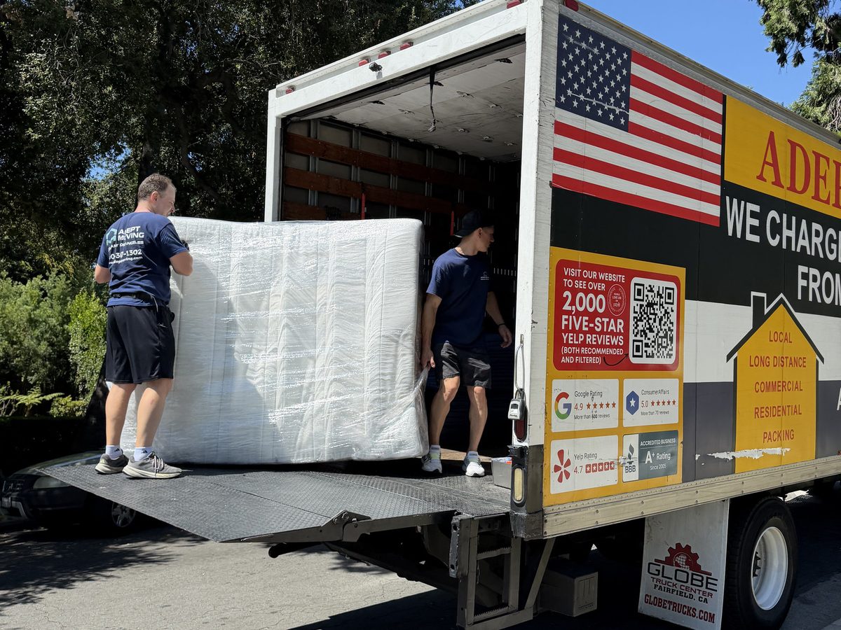 Adept Moving movers loading a stretch-wrapped king-size mattress onto the truck liftgate