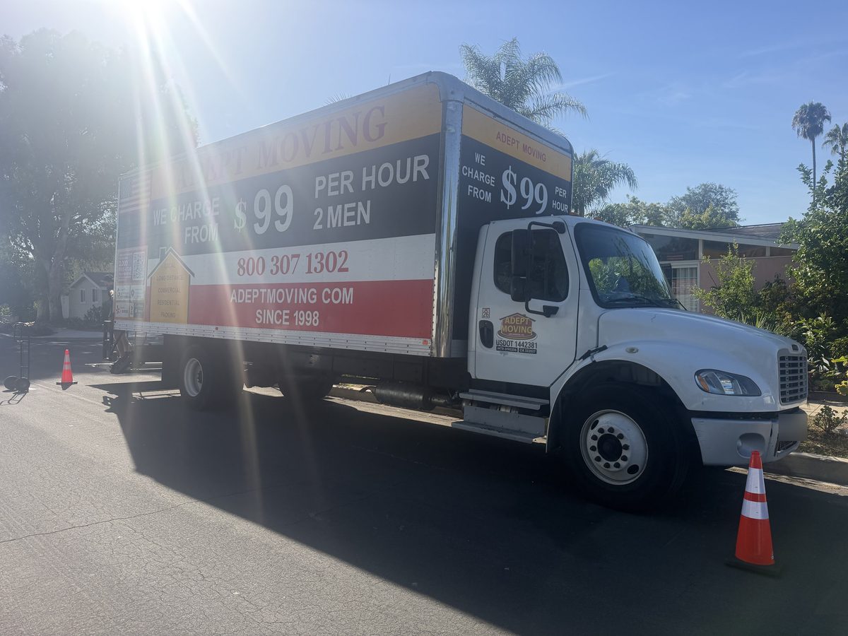 Adept Moving truck parked with cones near the curve of the street by the ranch home