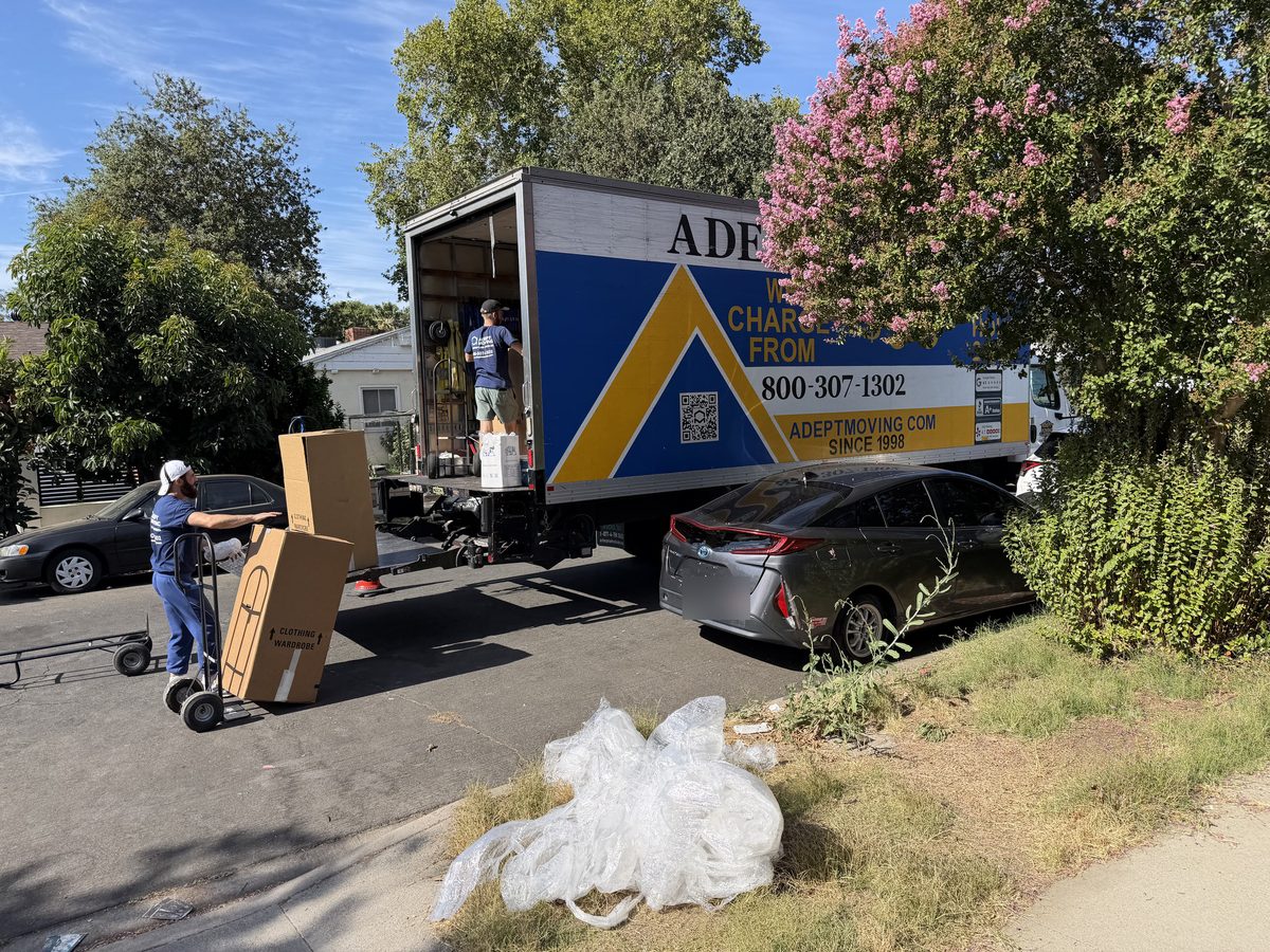 Adept Moving mover wheeling wardrobe cartons on a hand truck to the liftgate