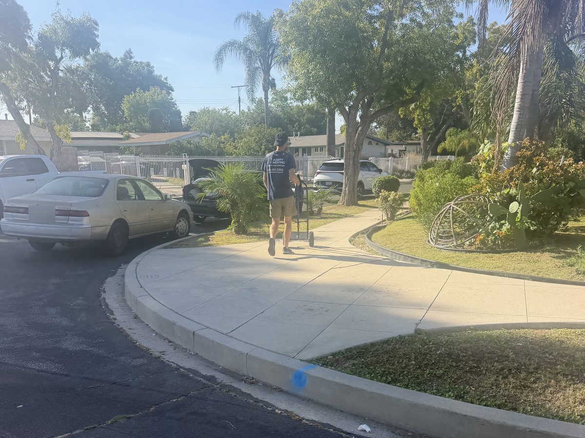 Adept Moving mover with a hand truck on the front walk of the ranch home