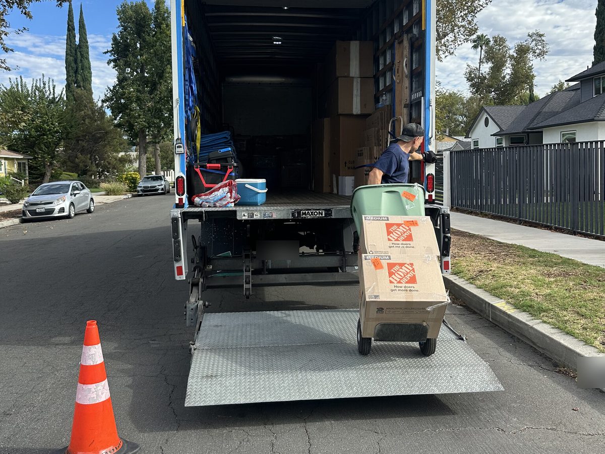 Adept Moving mover with boxes on a hand truck at the liftgate of the truck