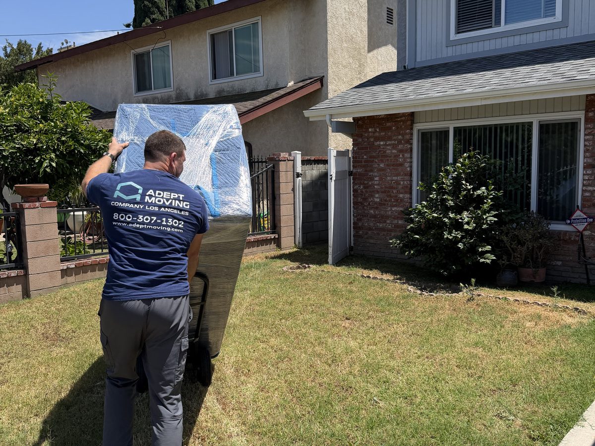 Adept Moving mover moving a wrapped piece across the front lawn on Leadwell Street