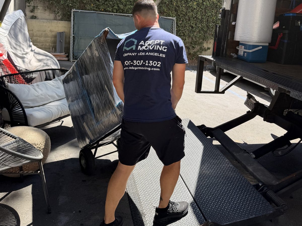 Adept Moving mover loading a blanket-wrapped piece at the truck liftgate on Sherman Way