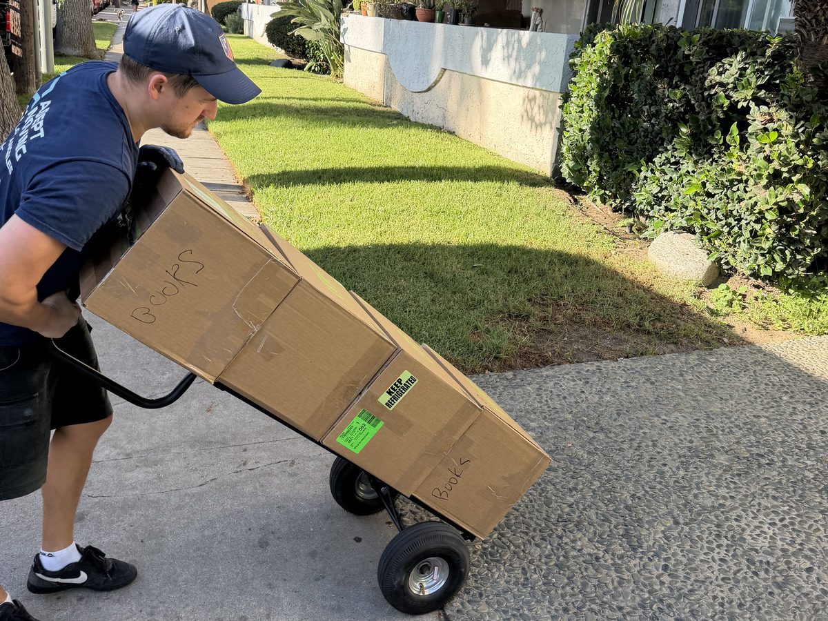 Adept Moving mover tilting a loaded hand truck by the apartment complex in Van Nuys